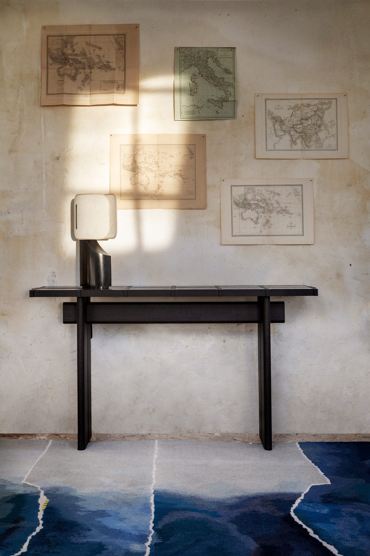Table console Terzo frêne teinté noir, lampe Faro bronze et tapis coban